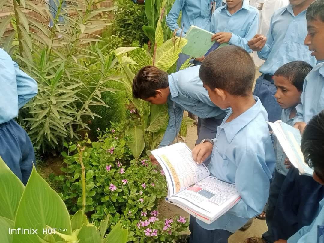 Students with books in school garden - environmental outdoor learning